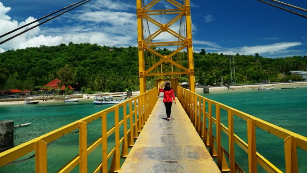 Tourist in red outfit taking photos at Yellow Bridge Lembongan, one of the island’s iconic landmarks