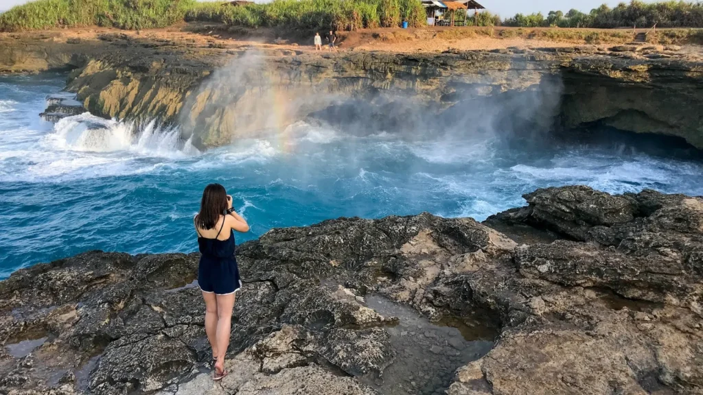 Woman capturing a moment at Devils Tear Nusa Lembongan, one of the island’s iconic natural attractions