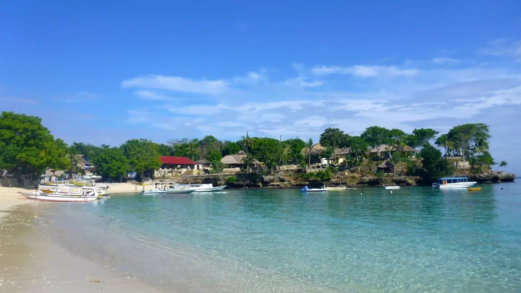Serene shoreline of Mushroom Bay Nusa Lembongan with traditional fishing boats anchored near the beach
