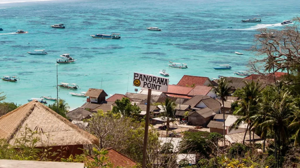 Panorama Point Nusa Lembongan overlooking blue ocean, sandy beach, and local houses from the cliff