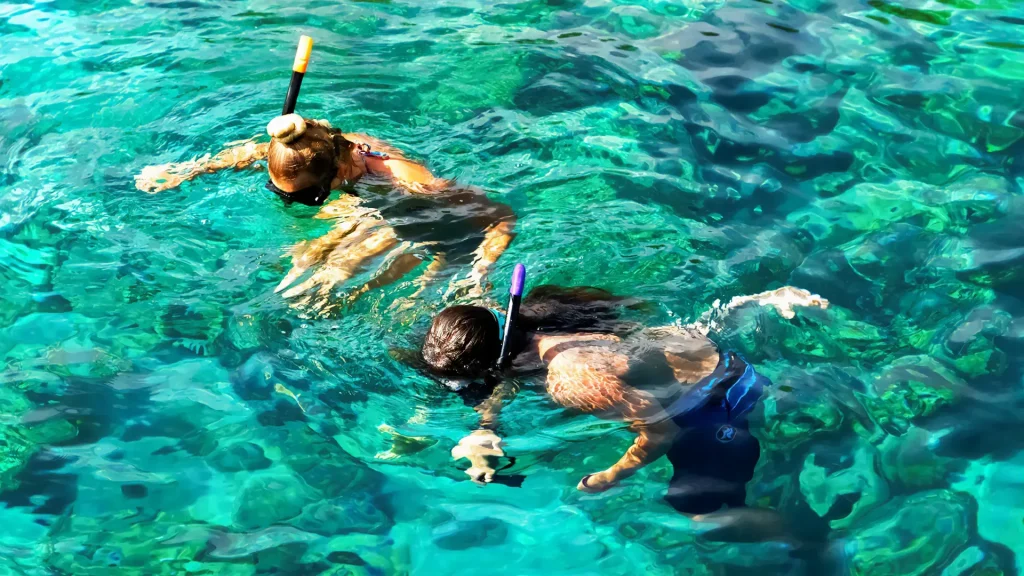 Two tourists snorkeling in crystal clear waters of Nusa Lembongan during Snorkeling in Nusa Lembongan activity