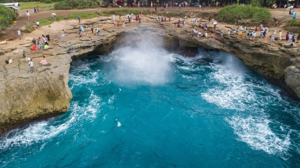Tourists enjoying ocean waves at the edge of Devils Tear Lembongan on Visit Devils Tear Lembongan experience